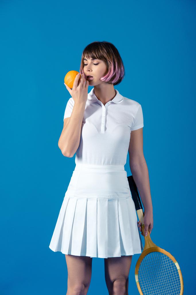 sexy Tennis player standing with orange isolated on blue - Photo, Image