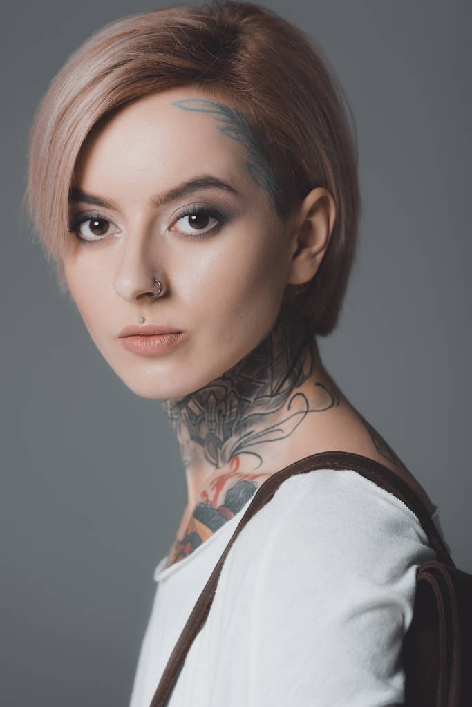 close-up portrait of beautiful young woman with tattoos looking at camera isolated on grey - Photo, Image