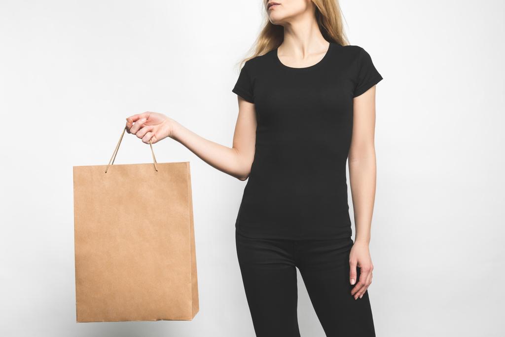 νεαρή γυναίκα στο κενό μαύρο t-shirt σε λευκό με τσάντα για ψώνια - Φωτογραφία, εικόνα