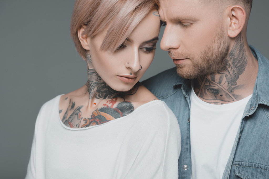 beautiful young tattooed couple in love posing together isolated on grey - Photo, Image