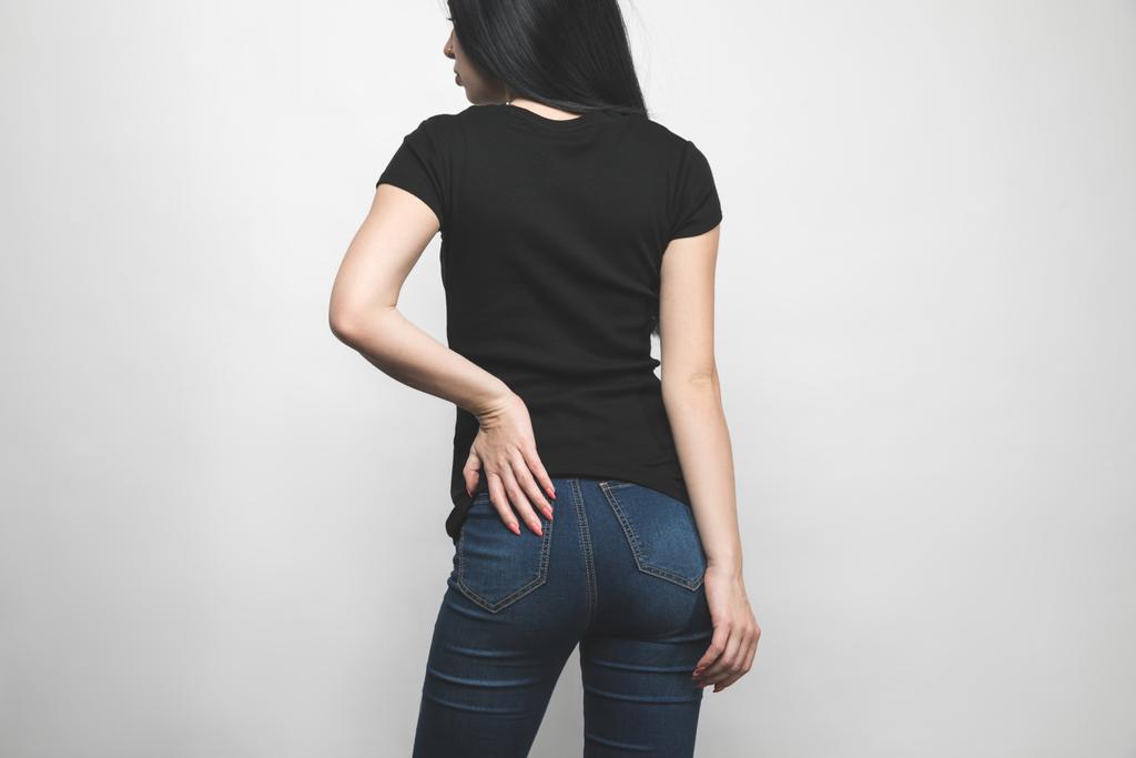 Rückansicht einer jungen Frau in leerem schwarzen T-Shirt isoliert auf weißem Grund - Foto, Bild