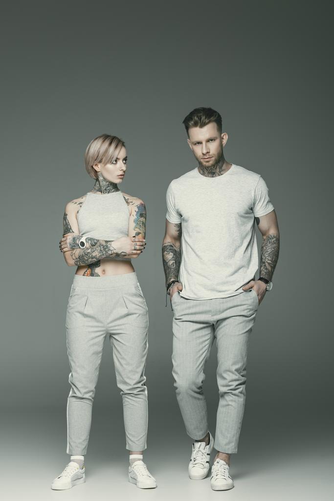 hermosa pareja tatuada en ropa deportiva posando juntos, aislado en gris
   - Foto, imagen