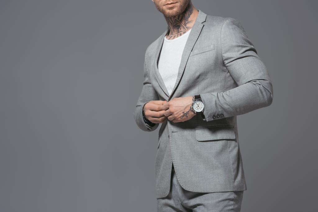 abgeschnittene Ansicht eines stilvollen Geschäftsmannes im grauen Anzug, isoliert auf grau - Foto, Bild
