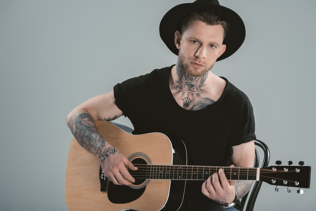 guitarrista tatuado em chapéu tocando na guitarra acústica, isolado em cinza
 - Foto, Imagem