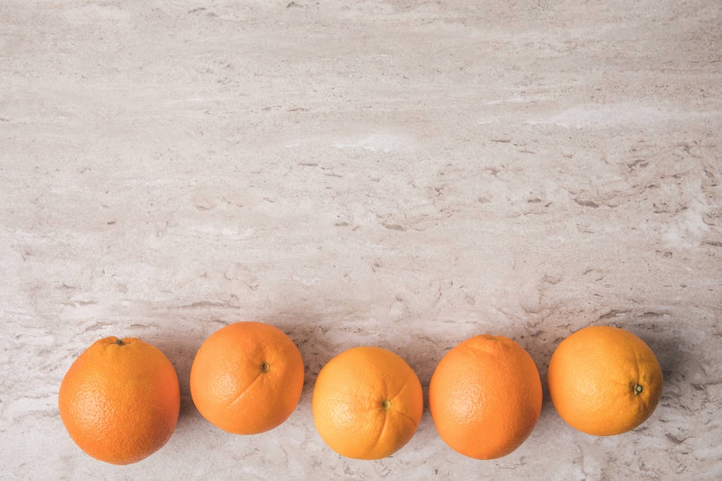 rij van sinaasappelen op marmeren oppervlak (bovenaanzicht) - Foto, afbeelding