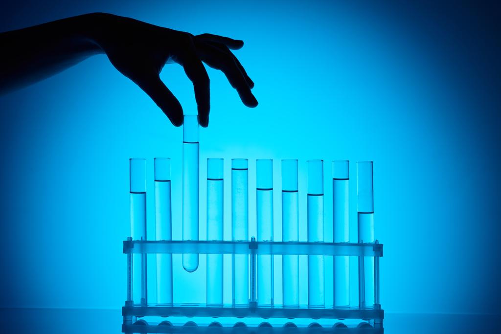 περικομμένη εικόνα χημικός λαμβάνοντας γυάλινο σωλήνα από στάση σε μπλε - Φωτογραφία, εικόνα