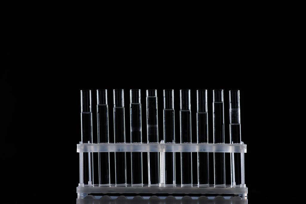 row of glass tubes with liquid on stand isolated on black - Photo, Image