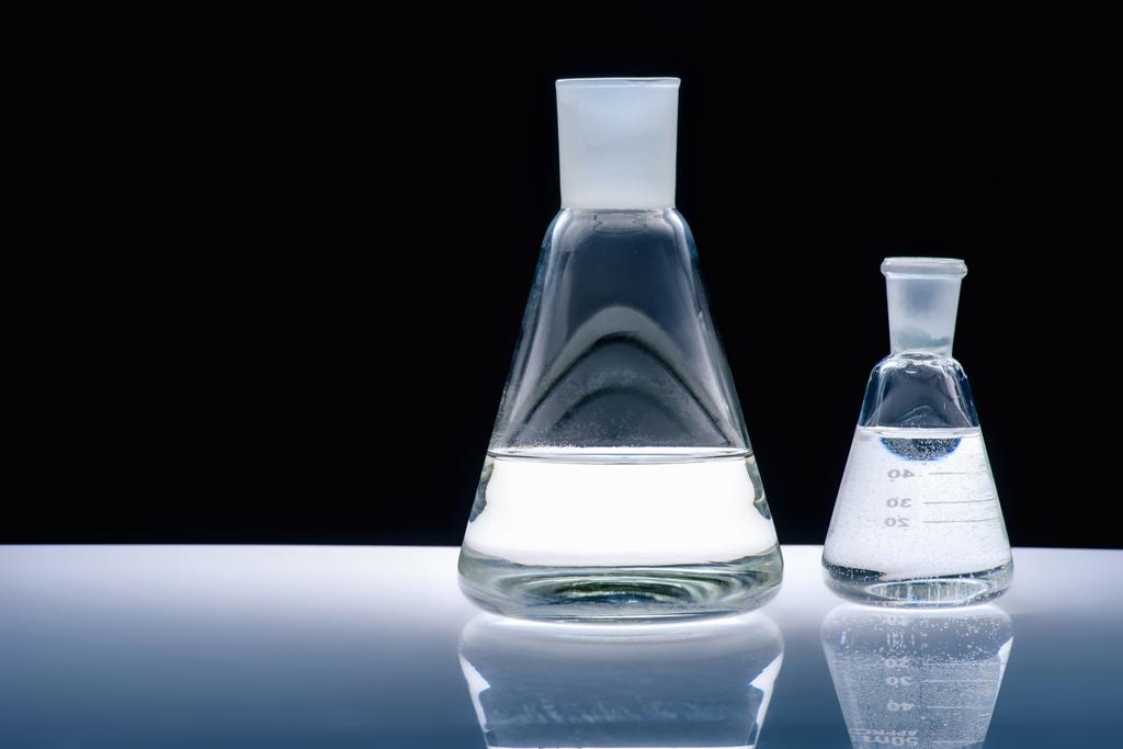 frascos de vidrio con líquido sobre mesa blanca sobre negro
 - Foto, imagen