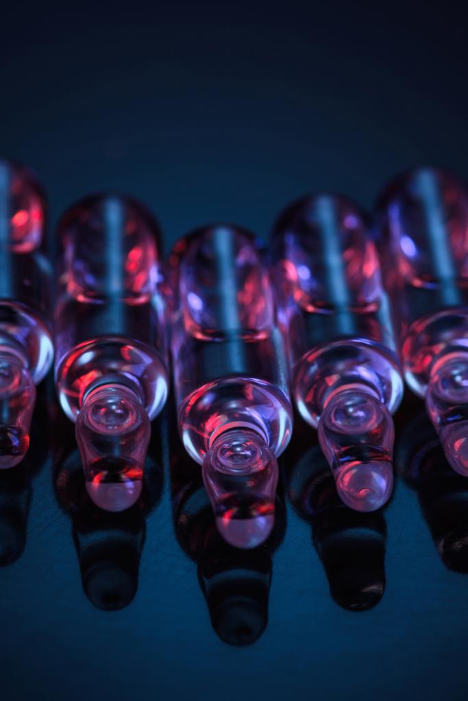 lähikuva läpinäkyvistä lasiampulleista, joissa on nestettä pöydällä
 - Valokuva, kuva