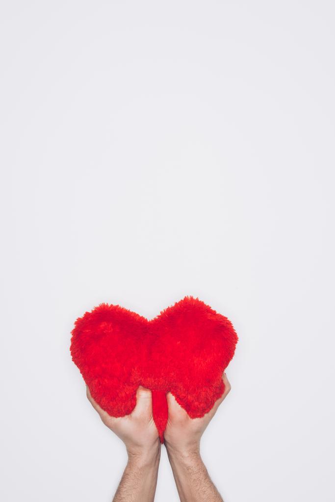 abgeschnittene Aufnahme eines Mannes, der weiches rotes Herzkissen isoliert auf Weiß drückt - Foto, Bild