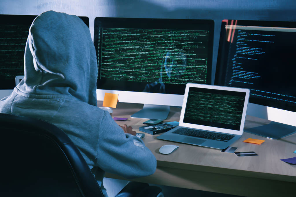 Mann mit Kapuzenpulli hackt Server im dunklen Raum - Foto, Bild