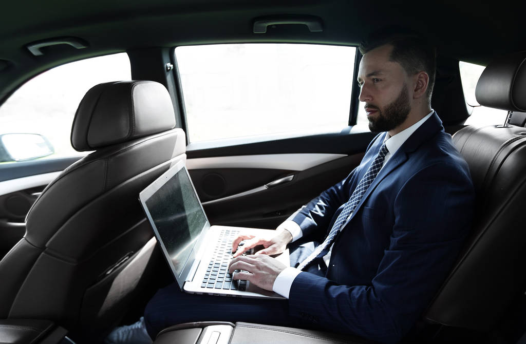 Бізнесмен використовує ноутбук на задньому сидінні автомобіля
 - Фото, зображення