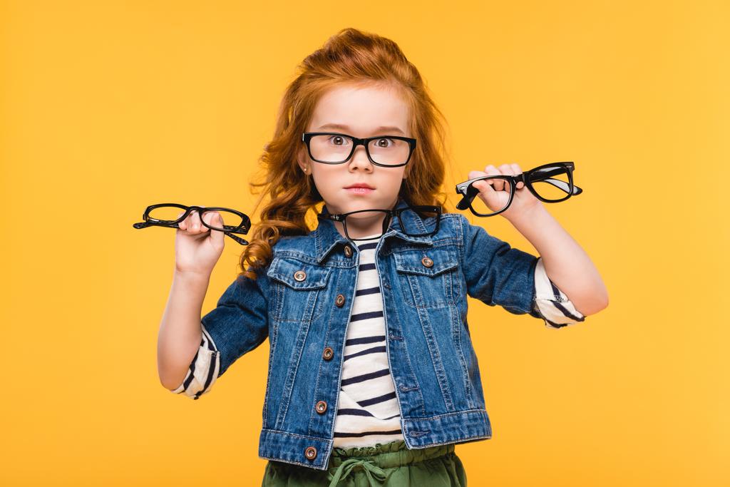 Sarı izole elinde gözlük gösterilen şok çocuk portresi - Fotoğraf, Görsel