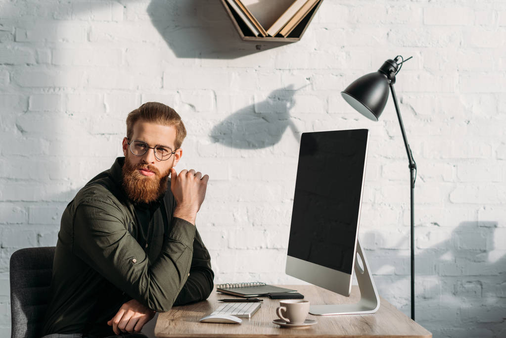 handsome bearded businessman sitting at working table and looking away - Photo, Image