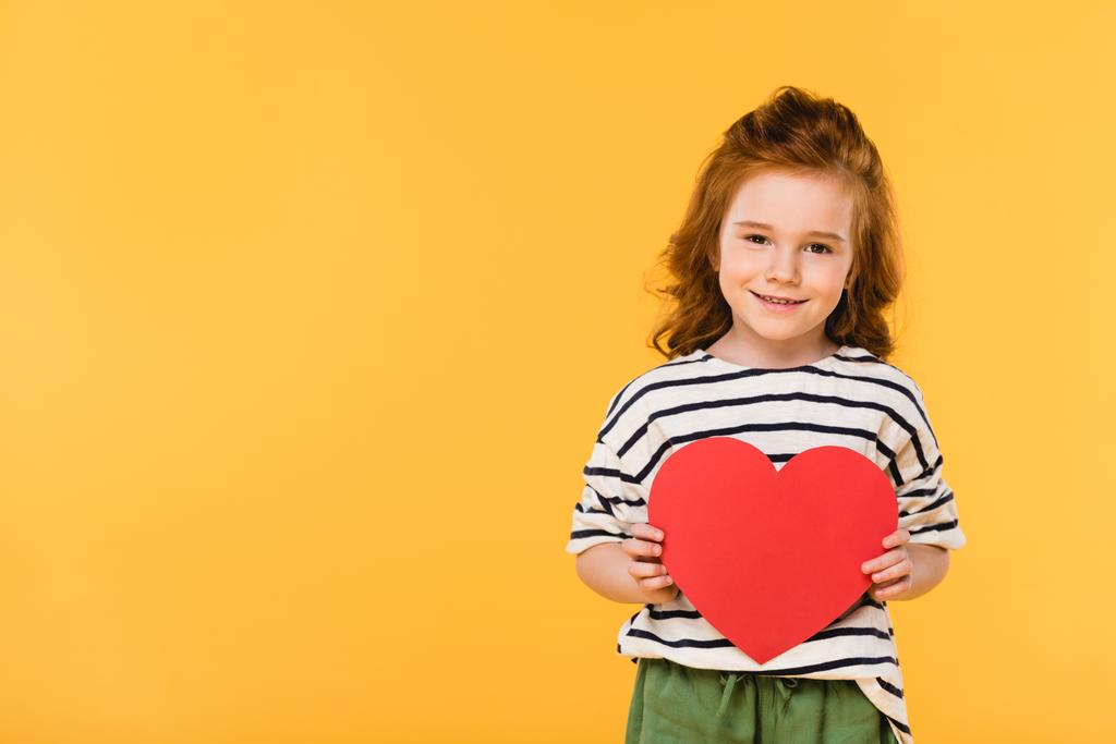 portrait of smiling kid with red paper heart isolated on yellow, st valentines day concept - Photo, Image