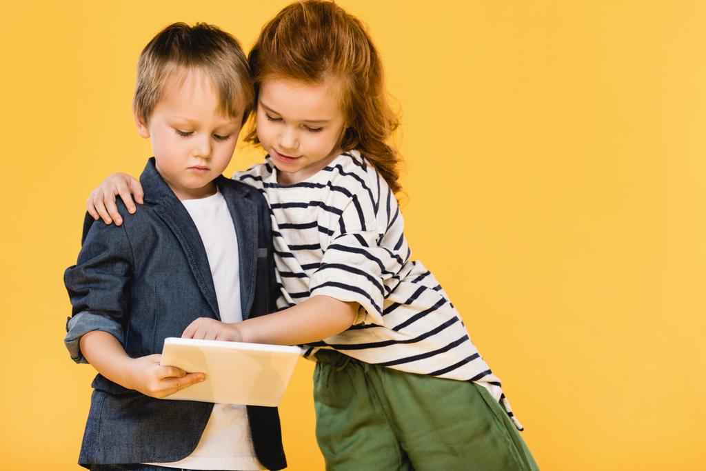 muotokuva lapsista, jotka käyttävät keltaisella eristettyä tablettia
 - Valokuva, kuva