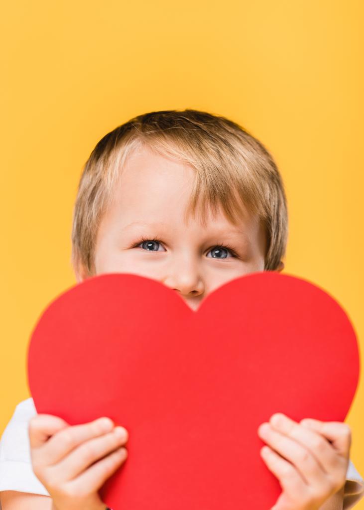 obscured view of boy covering face with red paper heart isolated on yellow, st valentines day concept - Photo, Image