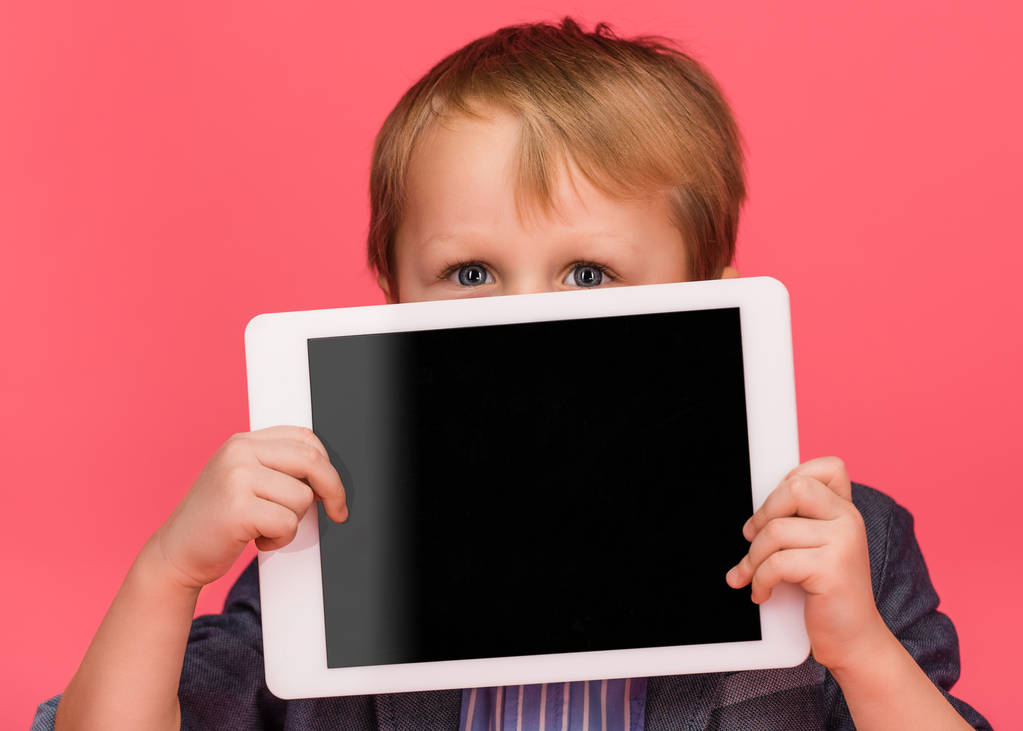 маленький мальчик покрывает лицо планшет с чистым экраном изолированы на розовый
 - Фото, изображение