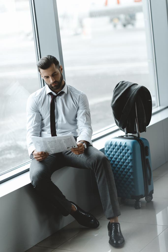 bell'uomo d'affari che legge il giornale mentre aspetta il volo nella hall dell'aeroporto
 - Foto, immagini