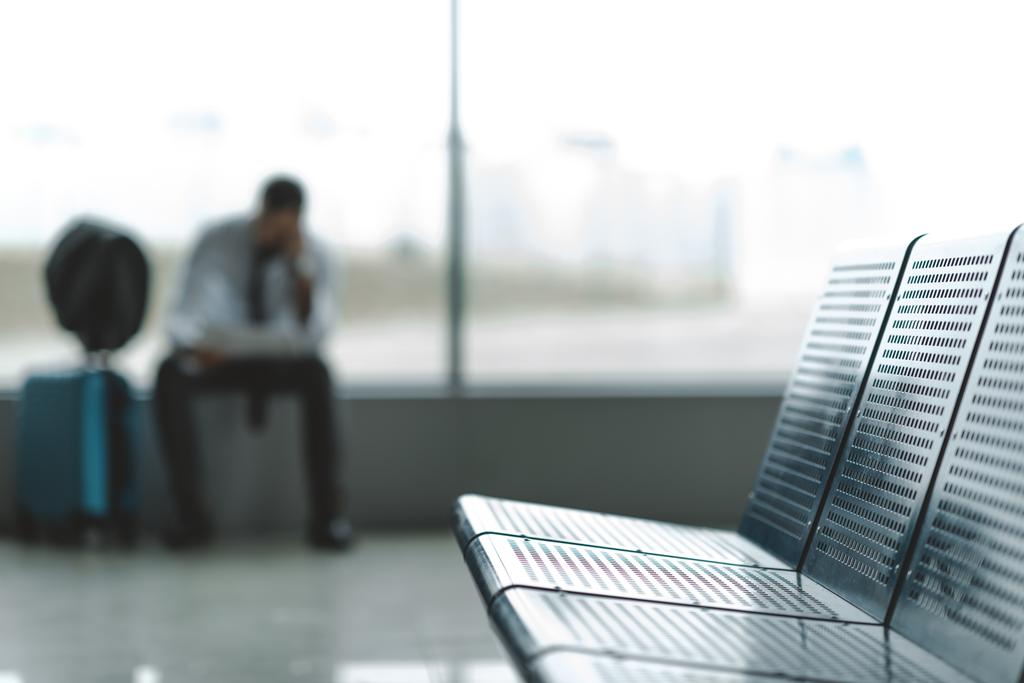 close-up shot of seats at airport lobby with buisnessman waiting for plane blurred on background - Photo, Image
