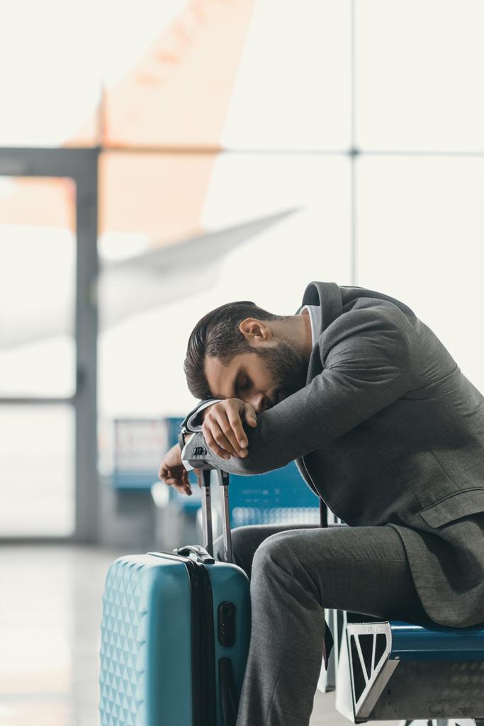 изнуренный бизнесмен спит в вестибюле аэропорта в ожидании рейса
 - Фото, изображение