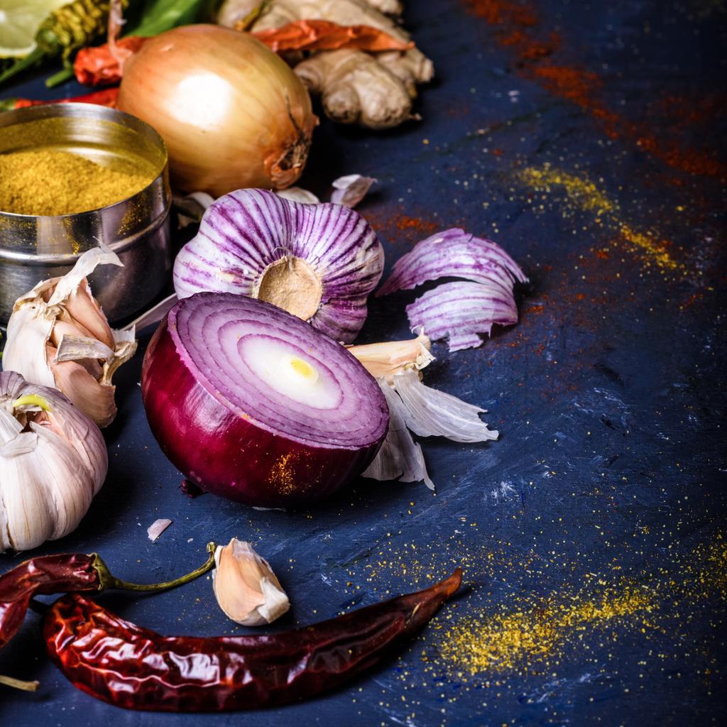 vergrote weergave van paprika, uien, knoflook, gember en curry poeder op blauw - Foto, afbeelding
