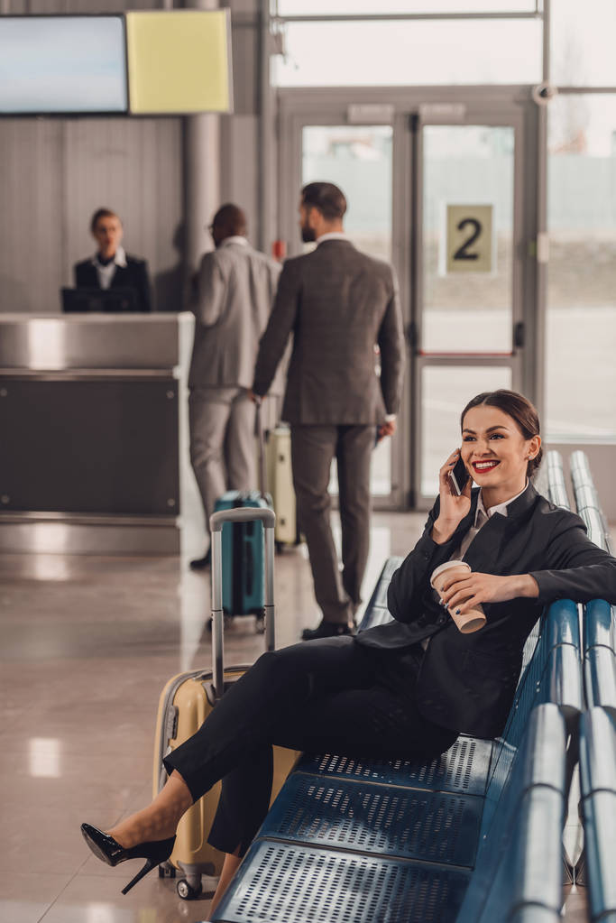 молода бізнес-леді чекає на літак у вестибюлі аеропорту і розмовляє по телефону
 - Фото, зображення