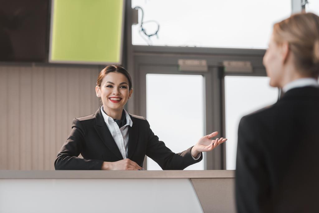 sorrindo recepcionista atraente aeroporto falando com o cliente
 - Foto, Imagem