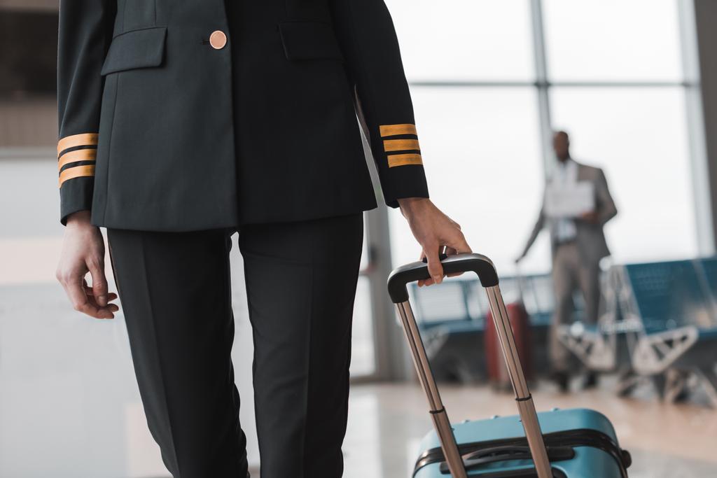 colpo ritagliato di pilota donna con valigia a piedi dalla hall dell'aeroporto
 - Foto, immagini