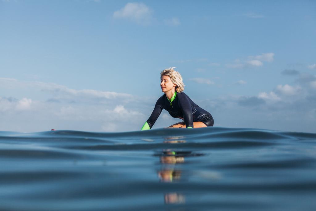 chica sentada en tabla de surf en el agua
 - Foto, Imagen