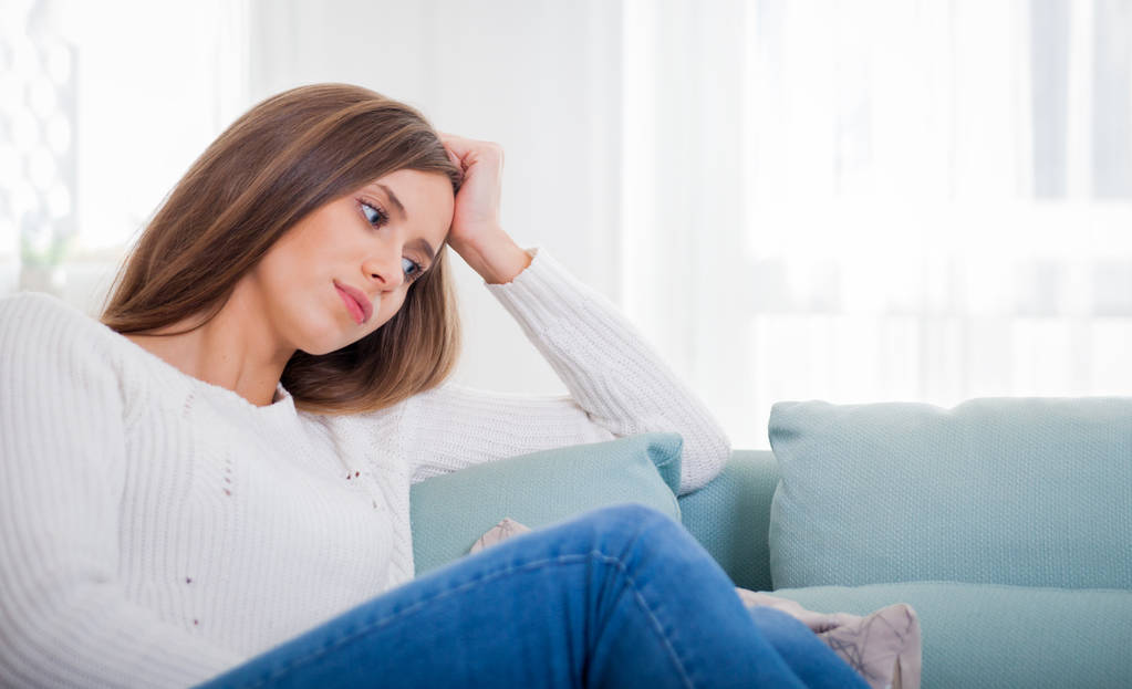 Smutná žena sedí na gauči doma hluboko v myšlenkách, přemýšlet o důležitých věcech - Fotografie, Obrázek