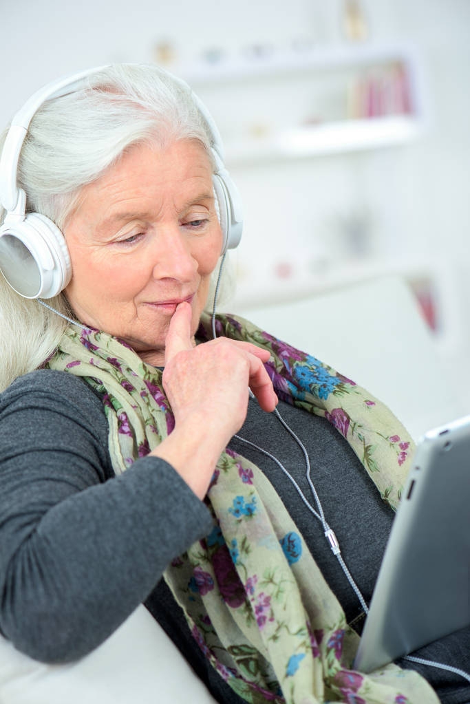 Mulher sênior feliz ouvindo música no tablet digital
 - Foto, Imagem