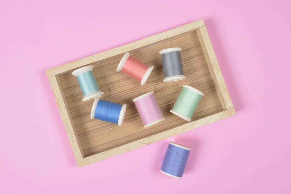 Colocación plana de rollos de hilo de colores para coser sobre fondo rosa
,  - Foto, imagen