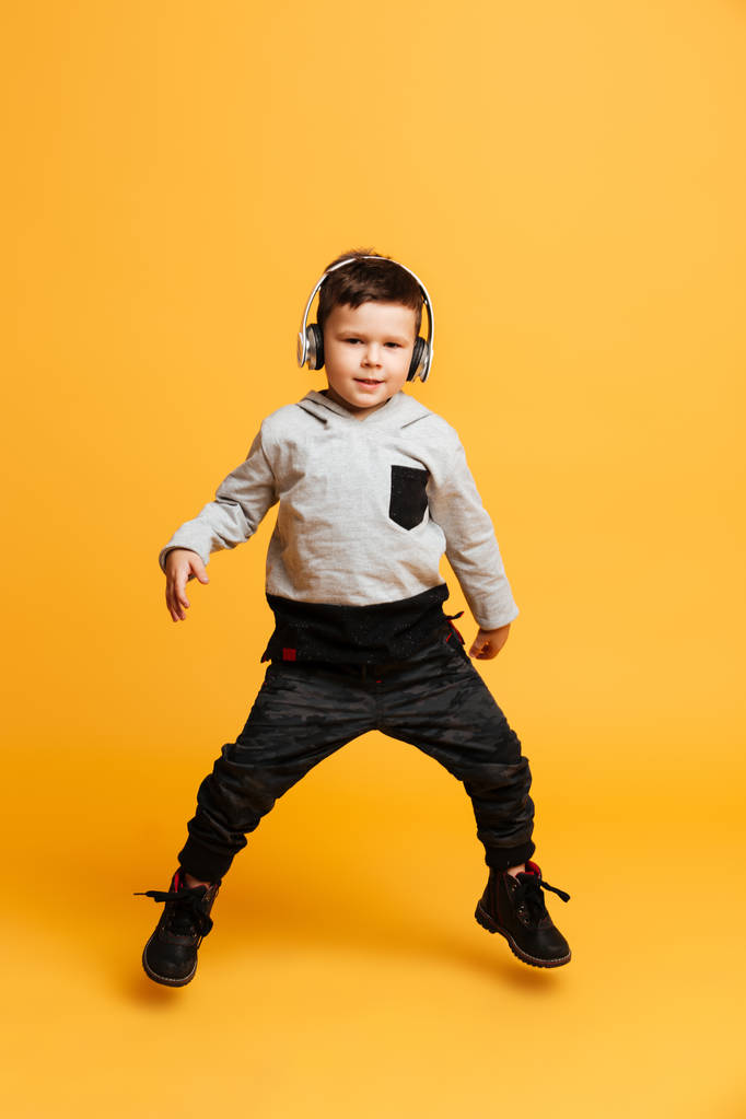 Хлопчик дитина стоїть ізольовано слухає музику з навушниками
. - Фото, зображення