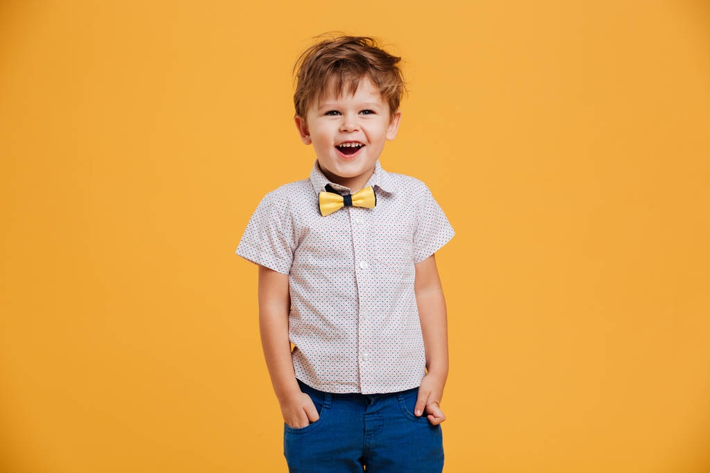 Смешной маленький мальчик стоял изолированный над желтым
 - Фото, изображение