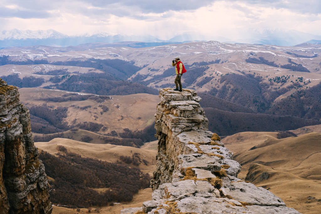 een man is een toerist die zich tegen een achtergrond van hoge bergen - Foto, afbeelding