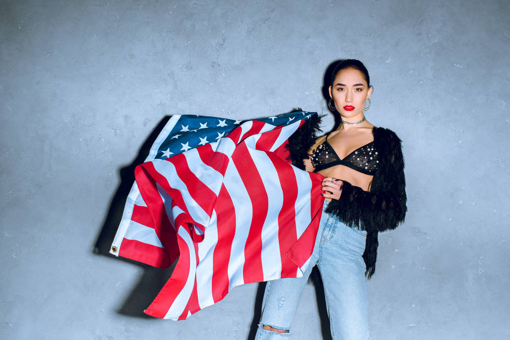 красивая азиатская женщина с американским флагом на бетонной стене
 - Фото, изображение
