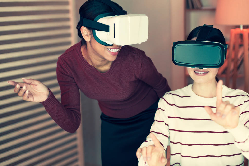 Duas jovens mulheres brincando com fones de ouvido VR e rindo
 - Foto, Imagem