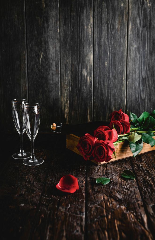κόκκινα τριαντάφυλλα και μπουκάλι σαμπάνιας και ποτήρια στο δίσκο, ιδέα του Αγίου Βαλεντίνου - Φωτογραφία, εικόνα