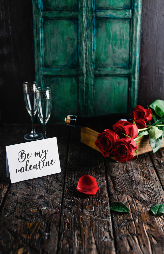 Sé mi tarjeta de felicitación de San Valentín, rosas rojas y botella de champán con copas en la mesa de mala calidad
 - Foto, Imagen