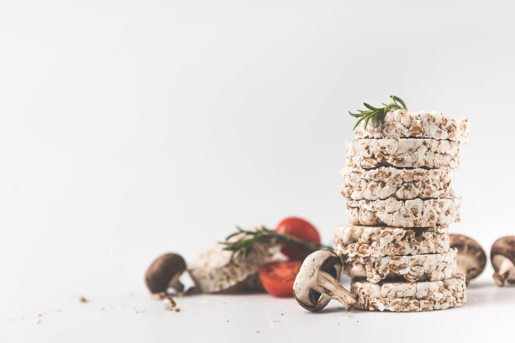 stapel rijstwafels met champignons en tomaten op witte ondergrond - Foto, afbeelding