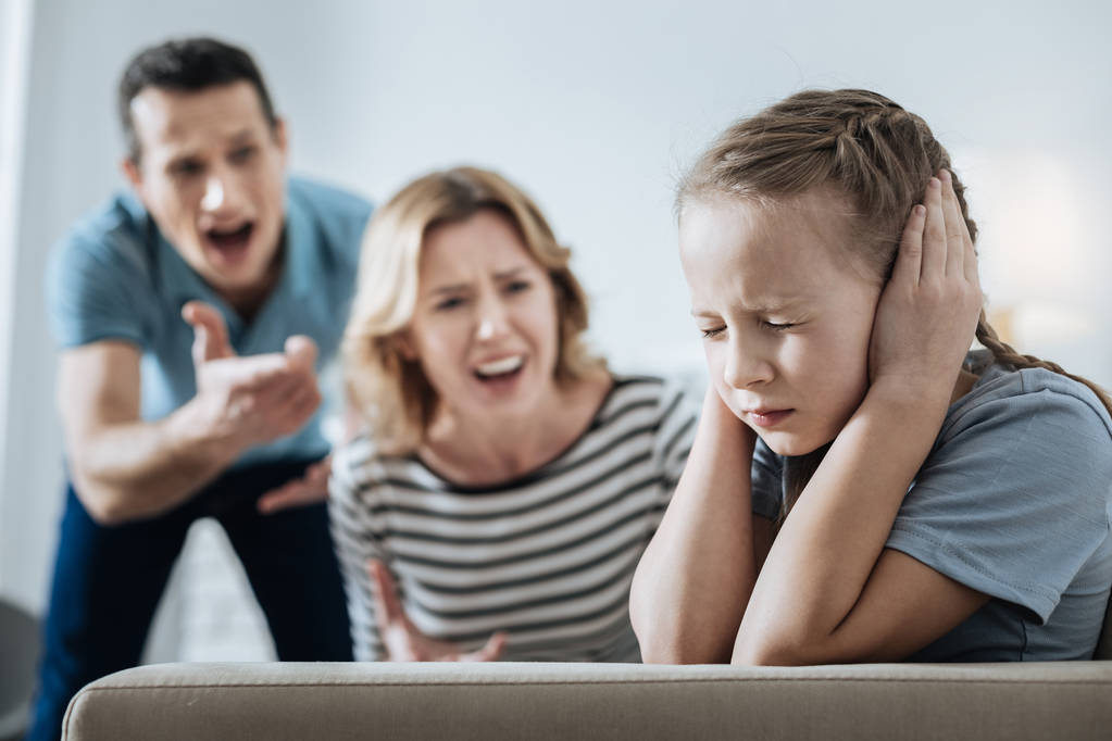 Menina triste e seus pais gritando com ela
 - Foto, Imagem