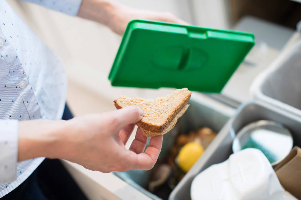 Cierre de la mujer poniendo residuos de alimentos en la papelera de reciclaje en la cocina
 - Foto, imagen