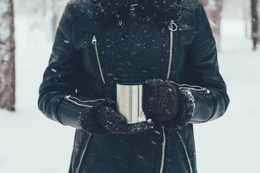 冬の日に熱い飲み物で魔法瓶を持っている女の部分的な眺め - 写真・画像
