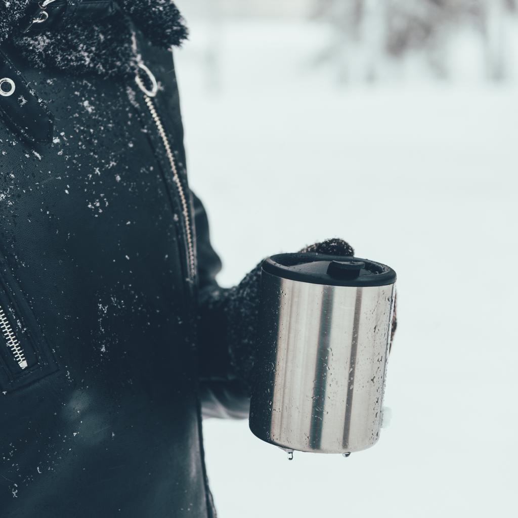 gedeeltelijk uitzicht op vrouw met thermocup met warme drank op winterdag - Foto, afbeelding