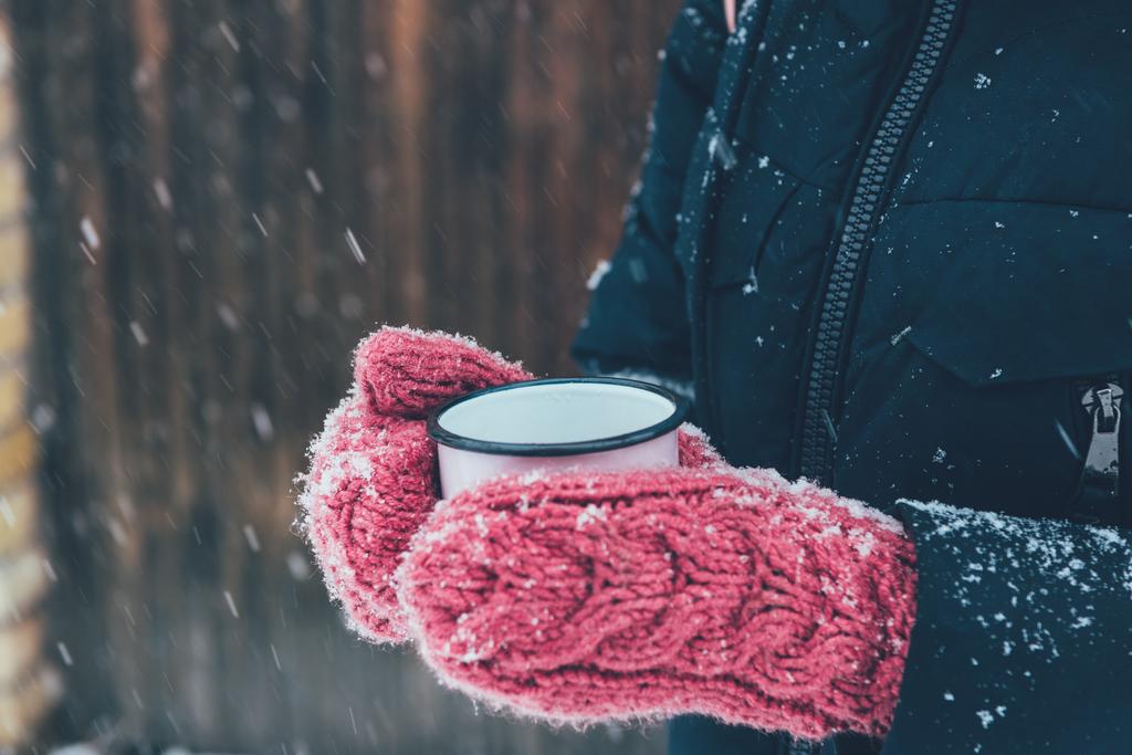 colpo ritagliato di donna che tiene in mano una tazza di tè nella giornata invernale
 - Foto, immagini