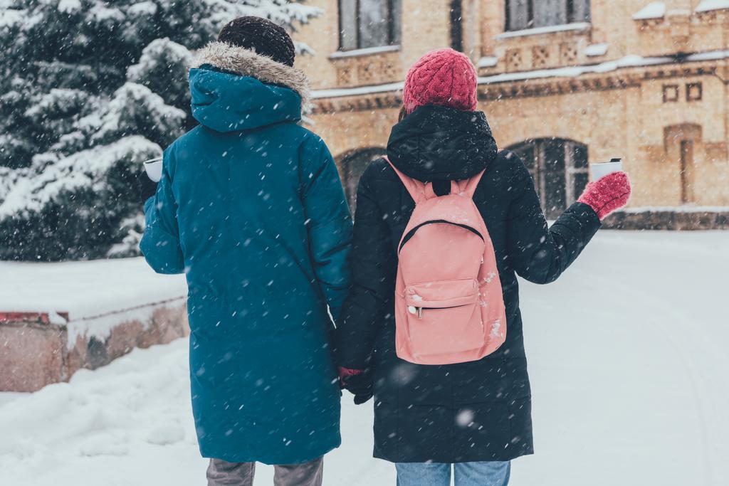 zadní pohled na páru s thermocups, drželi se za ruce v zimě - Fotografie, Obrázek
