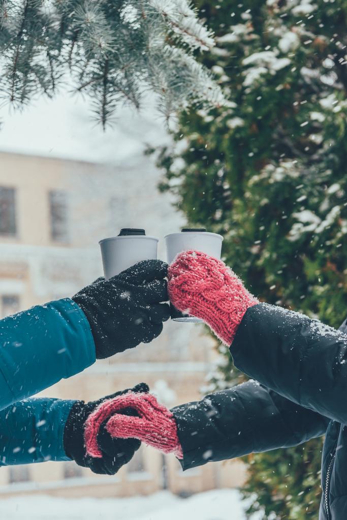 冬の路上の手を繋いでいるホットド リンクとカップルの部分的なビュー - 写真・画像