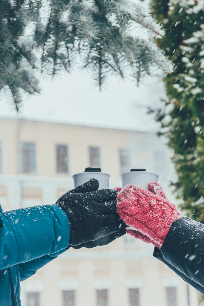 oříznuté záběr pár se drží thermocups s teplými nápoji na ulici v zimě - Fotografie, Obrázek