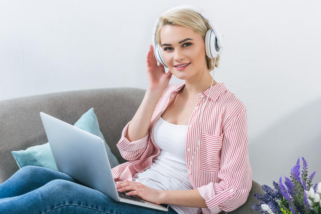 kaunis blondi tyttö kuuntelee musiikkia kuulokkeilla ja kannettavalla tietokoneella
 - Valokuva, kuva